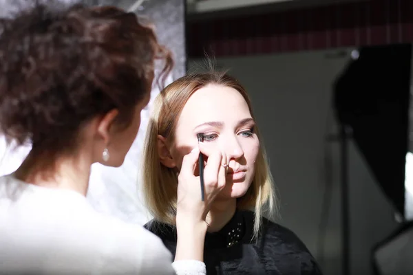 Ung flicka med en make-up artist — Stockfoto