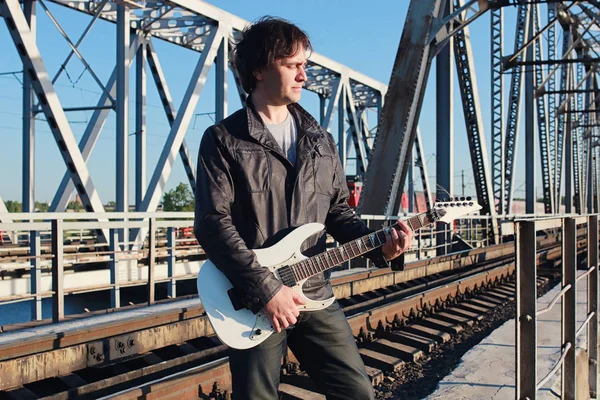 Homem com uma guitarra elétrica na paisagem industrial ao ar livre — Fotografia de Stock