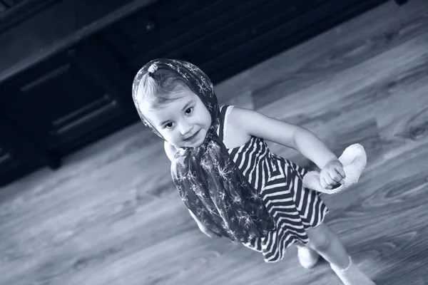Monokróm kép egy kislányról, aki ruhákban táncol a kezével. — Stock Fotó