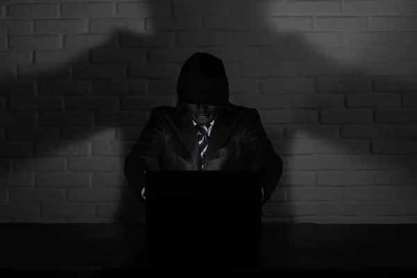 Хакер в чорній масці і капюшоні за столом — стокове фото