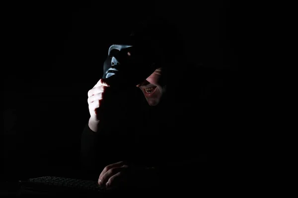 Seorang pria dalam cetakan topeng di keyboard dalam gelap — Stok Foto