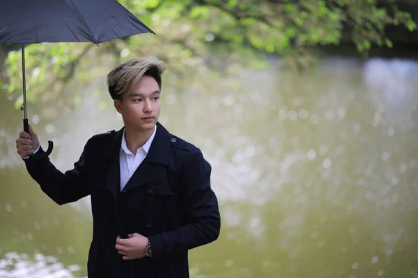 Printemps temps pluvieux et un jeune homme avec un parapluie — Photo