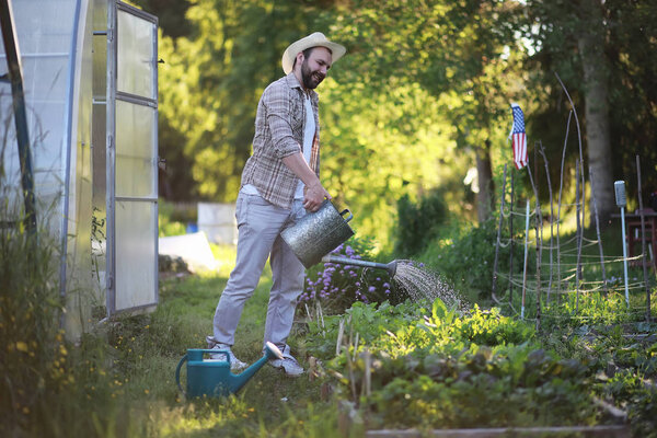 Человек-фермер поливает огород
