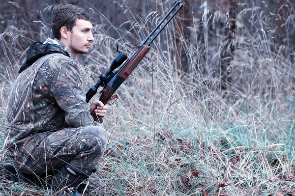Человек в камуфляже и с охотничьей винтовкой в лесу на сандвиче — стоковое фото