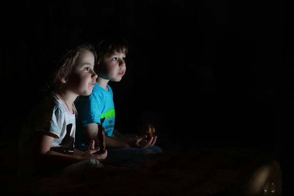 Niños pequeños en una habitación oscura viendo la televisión —  Fotos de Stock