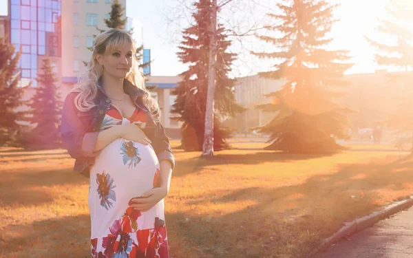 怀孕的女孩在公园里散步。女孩与腹部在词 — 图库照片