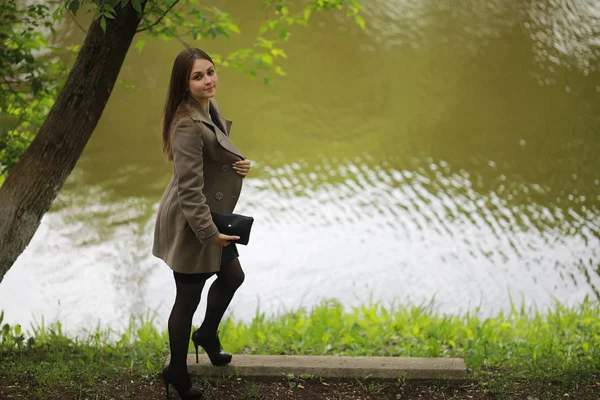 Chica joven en un abrigo en un parque de primavera — Foto de Stock