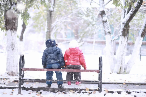 Dzieci chodzą w parku pierwszy śnieg — Zdjęcie stockowe