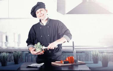 Adam mutfak masasında sebze pişiriyor.