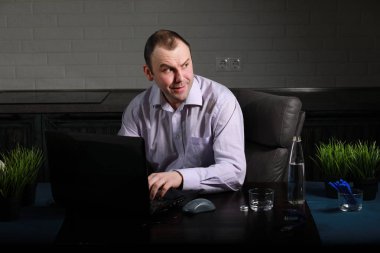 Masada oturan ve dizüstü bilgisayarda çalışan adam