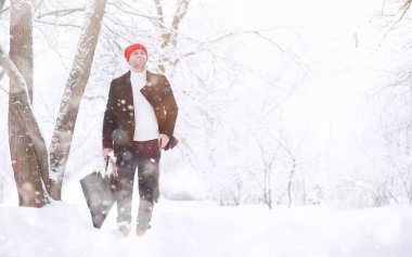 Parkta yürüyen bir adam. Genç adam kışın karla kaplı