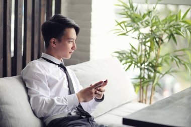 Genç bir Asyalı işadamı bir kafede ortak bekliyor. Bir kafede Koreli genç bir adam telefonda konuşuyor.