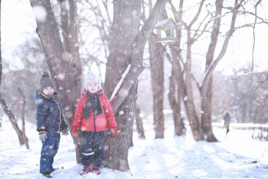 Çocuklar parkta kuşları besler. 