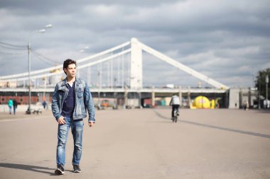 Genç bir adam öğle yemeği zamanında parkta yürür. Bir adam yürüyüşe çıktı. 