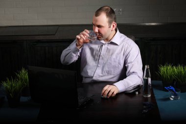 Masada oturan ve dizüstü bilgisayarda çalışan adam