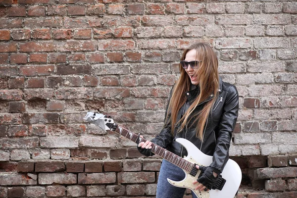 Uma menina músico de rock em uma jaqueta de couro com uma guitarra — Fotografia de Stock