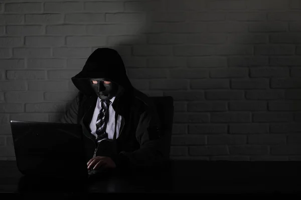 Siyah maske ve hood masada hacker — Stok fotoğraf