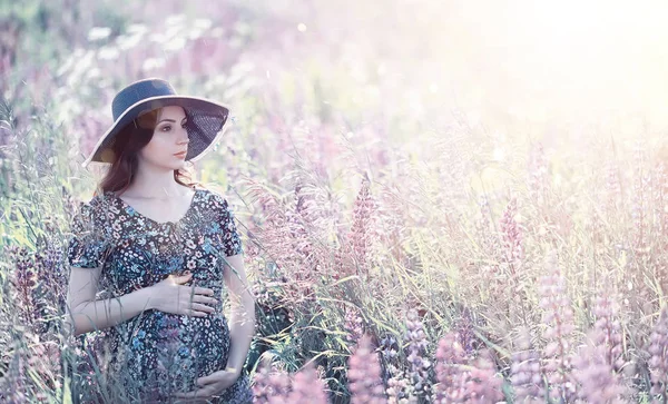 Gravid flicka i ett fält med blommor — Stockfoto