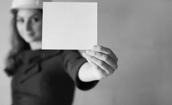Menina com uma folha de papel em branco em sua mão na construção sentar — Fotografia de Stock
