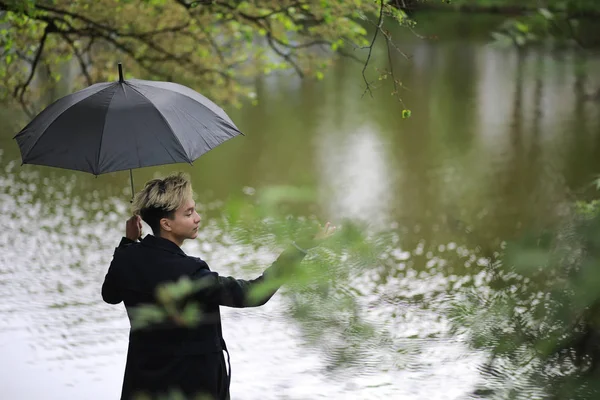Tavaszi záporok és egy fiatal ember, egy esernyő — Stock Fotó