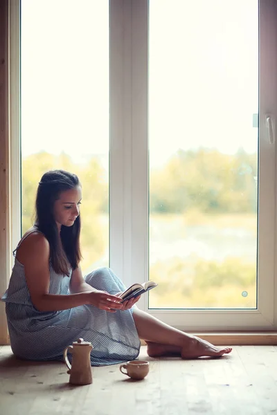 En flicka på fönstret i huset — Stockfoto