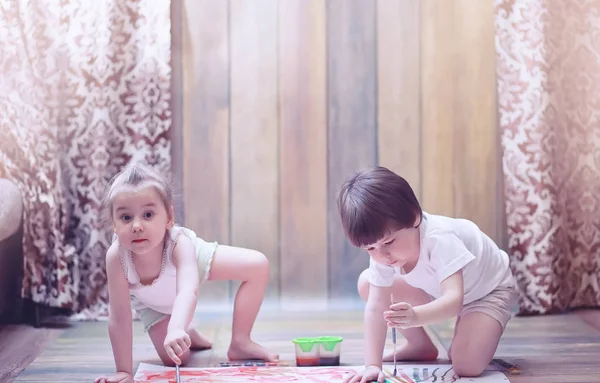 Niños pequeños pintan en una hoja grande de papel —  Fotos de Stock