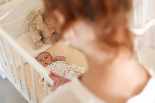 갓난귀여운 아기가 요람에 누워 있고 보고 있는 엄마 — 스톡 사진
