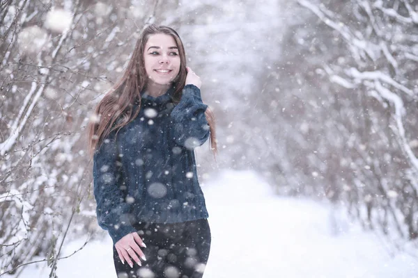 Flicka i en vinterpark i snöfall — Stockfoto