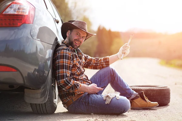 Man sitter på vägen av bilen — Stockfoto