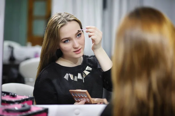 Uma jovem faz maquiagem em um salão de beleza. A menina na frente o — Fotografia de Stock