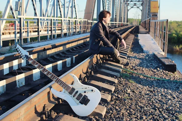 Muž s elektrickou kytaru v průmyslové krajině venku — Stock fotografie