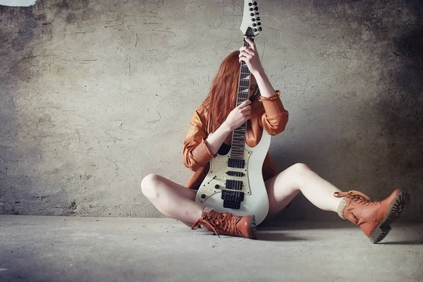 Ung rødhåret pige med en elektrisk guitar. Rock musiker gir - Stock-foto