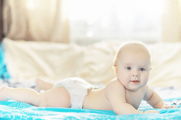 A newborn baby is lying on a soft bed. Children's emotions.