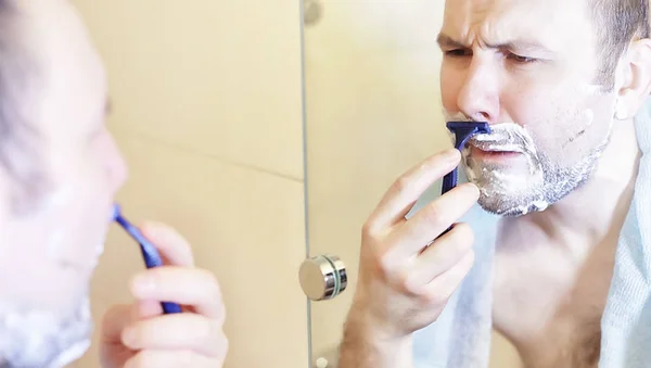 Egy férfi reggel borotválkozik a fürdőszobában. — Stock Fotó