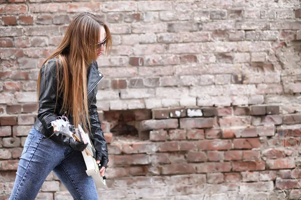 Una chica músico de rock en una chaqueta de cuero con una guitarra — Foto de Stock