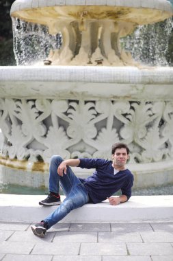 Genç bir adam öğle yemeği zamanında parkta yürür. Bir adam yürüyüşe çıktı. 