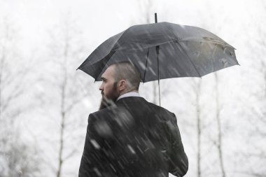 Takım elbiseli kel sakallı bir adam.