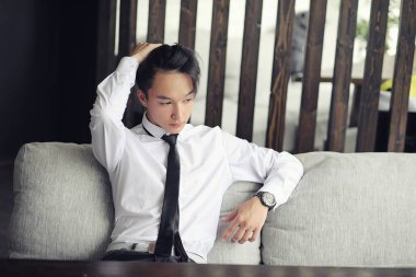 Genç bir Asyalı işadamı bir kafede ortak bekliyor. Bir kafede Koreli genç bir adam telefonda konuşuyor.