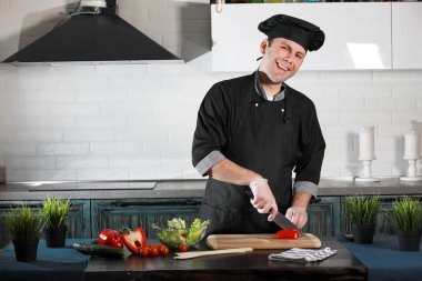 Adam mutfak masasında sebze pişiriyor.