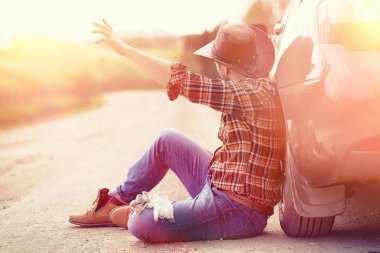 Adam yolda arabanın yanında oturuyor