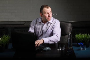 Masada oturan ve dizüstü bilgisayarda çalışan adam