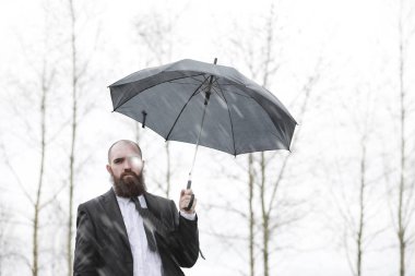 Takım elbiseli kel sakallı bir adam.