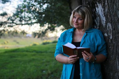 kadınla çimenlerin üzerinde kitapla Park