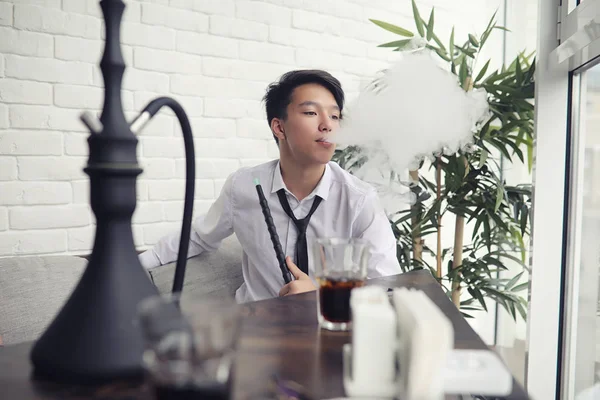 A young Asian businessman is waiting for a partner in a cafe. A Korean young man talking on the phone in a cafe