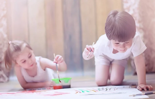 Pienet lapset maalaavat suurelle paperiarkille — kuvapankkivalokuva