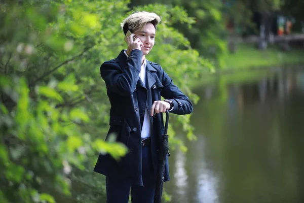 Primavera tempo piovoso e un giovane uomo con un ombrello — Foto Stock