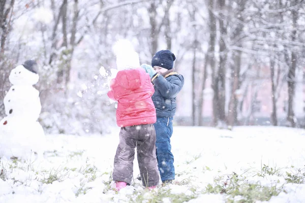 Дети ходят по парку первым снегом — стоковое фото