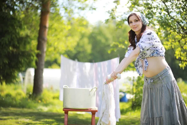 Pregnant woman hanging wash clothes on the rope for drying