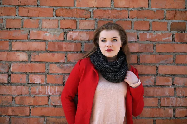 Cute girl in red coat on brick wall — Stock Photo, Image