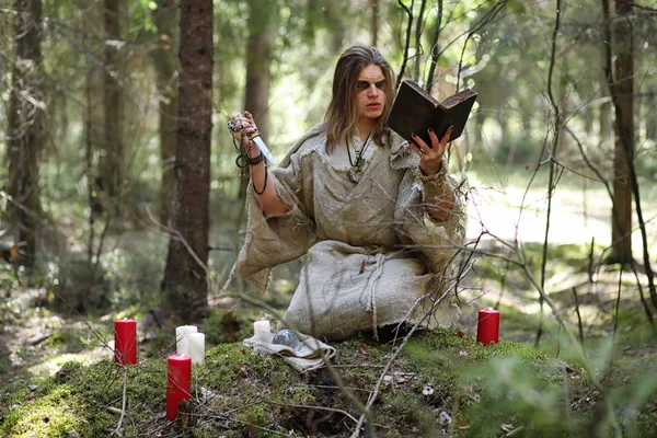 Un homme en soutane passe un rituel dans une forêt sombre — Photo